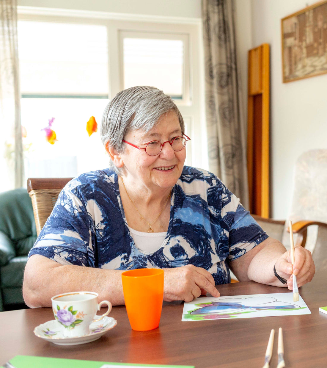 blije oudere mevrouw die schildert met water